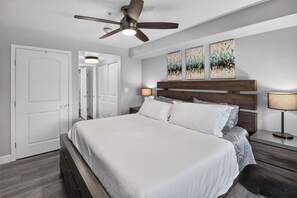 A bedroom with a bed, a ceiling fan, a nightstand, a lamp, and a door. - First Tracks at Wildhorse | Gondola + Hot Tubs (Steamboat Springs)