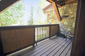 A wooden deck with a stone wall and a metal railing. - First Tracks at Wildhorse | Gondola + Hot Tubs (Steamboat Springs)