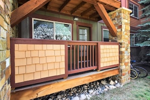A wooden deck with a stone pillar and a bicycle parked nearby. - First Tracks at Wildhorse | Gondola + Hot Tubs (Steamboat Springs)
