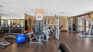 Ein Fitnessstudio mit verschiedenen Trainingsgeräten, einem blauen Übungsball und Laufbändern.