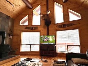 Un intérieur en bois, orné d’une tête de cerf fixée au mur, d’un téléviseur et d’une cheminée.