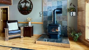 Een gezellige kamer met een stenen openhaard, een houten bank, een kleine tafel met een vaas en een wandheater.