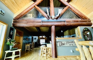 Un intérieur rustique avec une structure de plafond en bois, un espace bar et un coin salon.