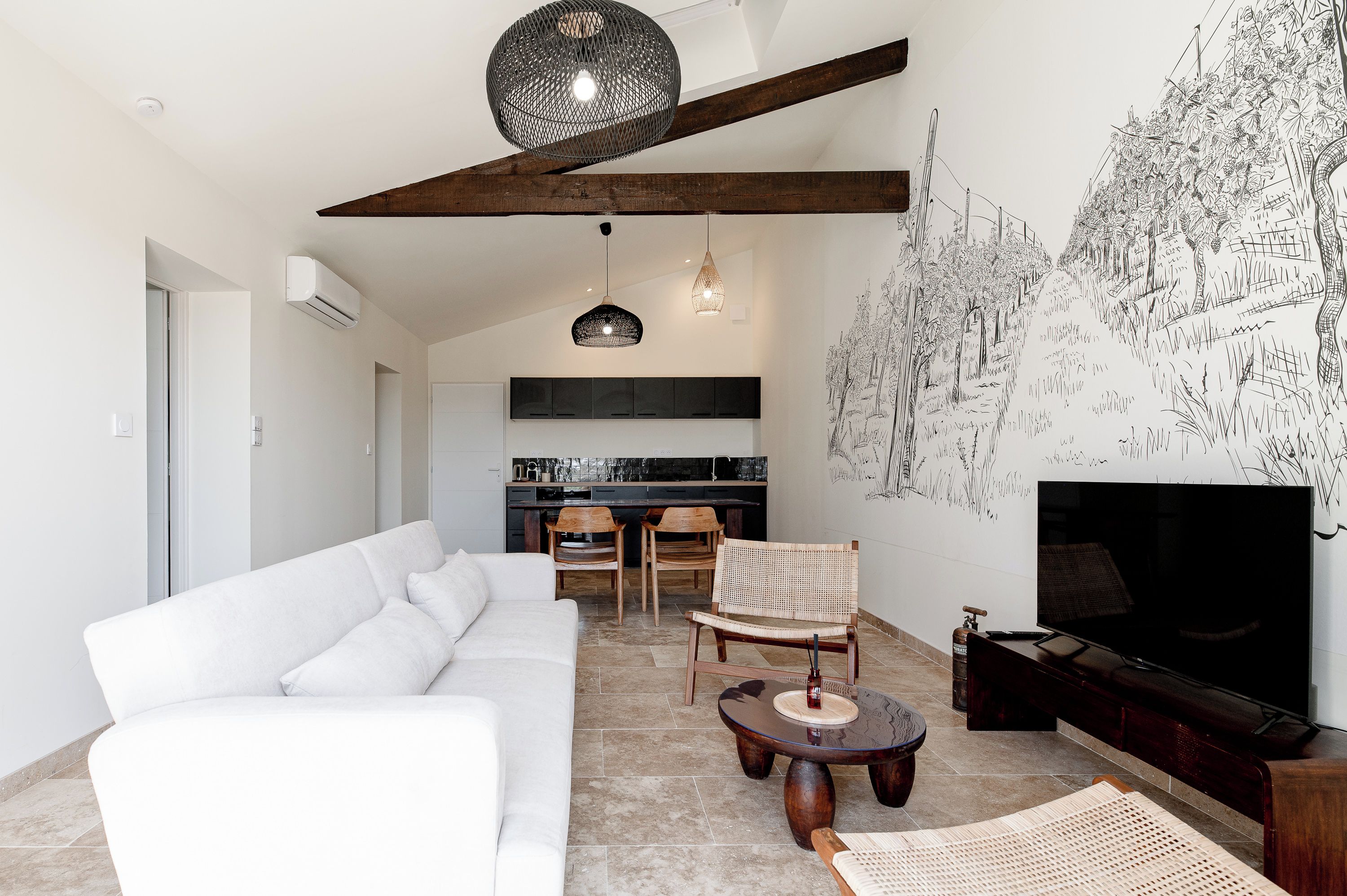 Uma sala de estar moderna com um sofá branco, uma mesa de jantar de madeira com cadeiras, uma TV e uma parede com um mural em preto e branco.