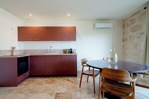 A modern kitchen with a dining area, featuring a dishwasher, a sink, and a coffee machine. - Le Chai de Canteloup (Yvrac)