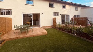 Een huis met twee verdiepingen, een terras, een kleine tuin en een schuifdeur naar een keuken.