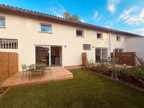 A two-story house with a patio, a small garden, and a sliding glass door leading to a kitchen.