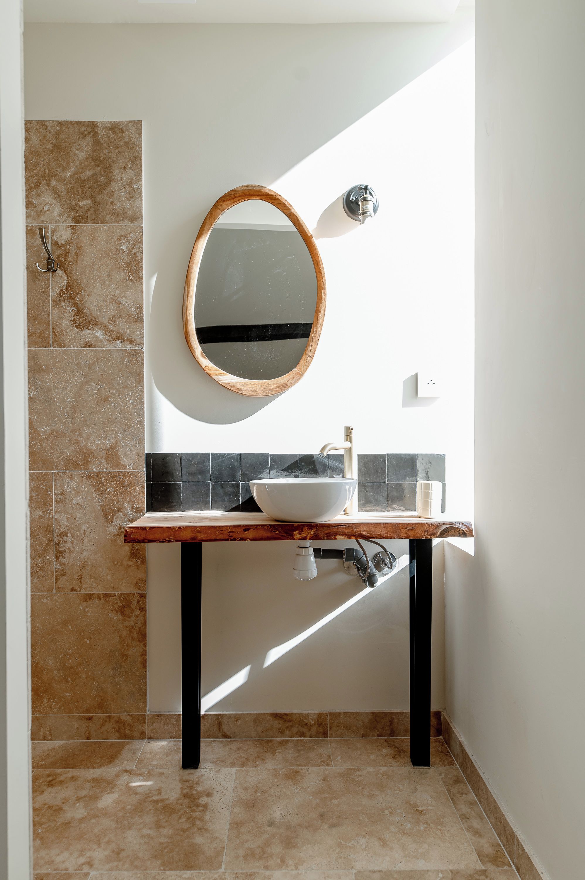 Une salle de bain avec un meuble-lavabo en bois, un miroir rond et un lavabo blanc.