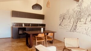Een moderne keuken met donkere kastjes, een centraal eiland en een eetgedeelte met een bank en stoelen.