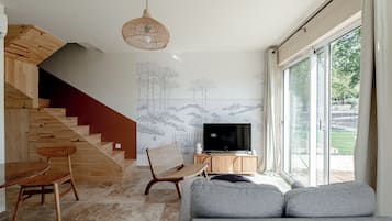 Sala moderna com escada, televisão de tela plana e uma grande janela.