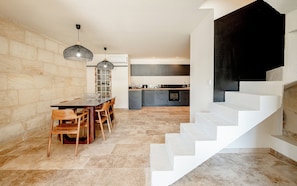 Una cocina moderna con armarios grises, una mesa de comedor con sillas y una escalera con escalones blancos.