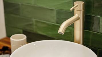 A white ceramic sink with a single faucet, set against a green tiled wall.