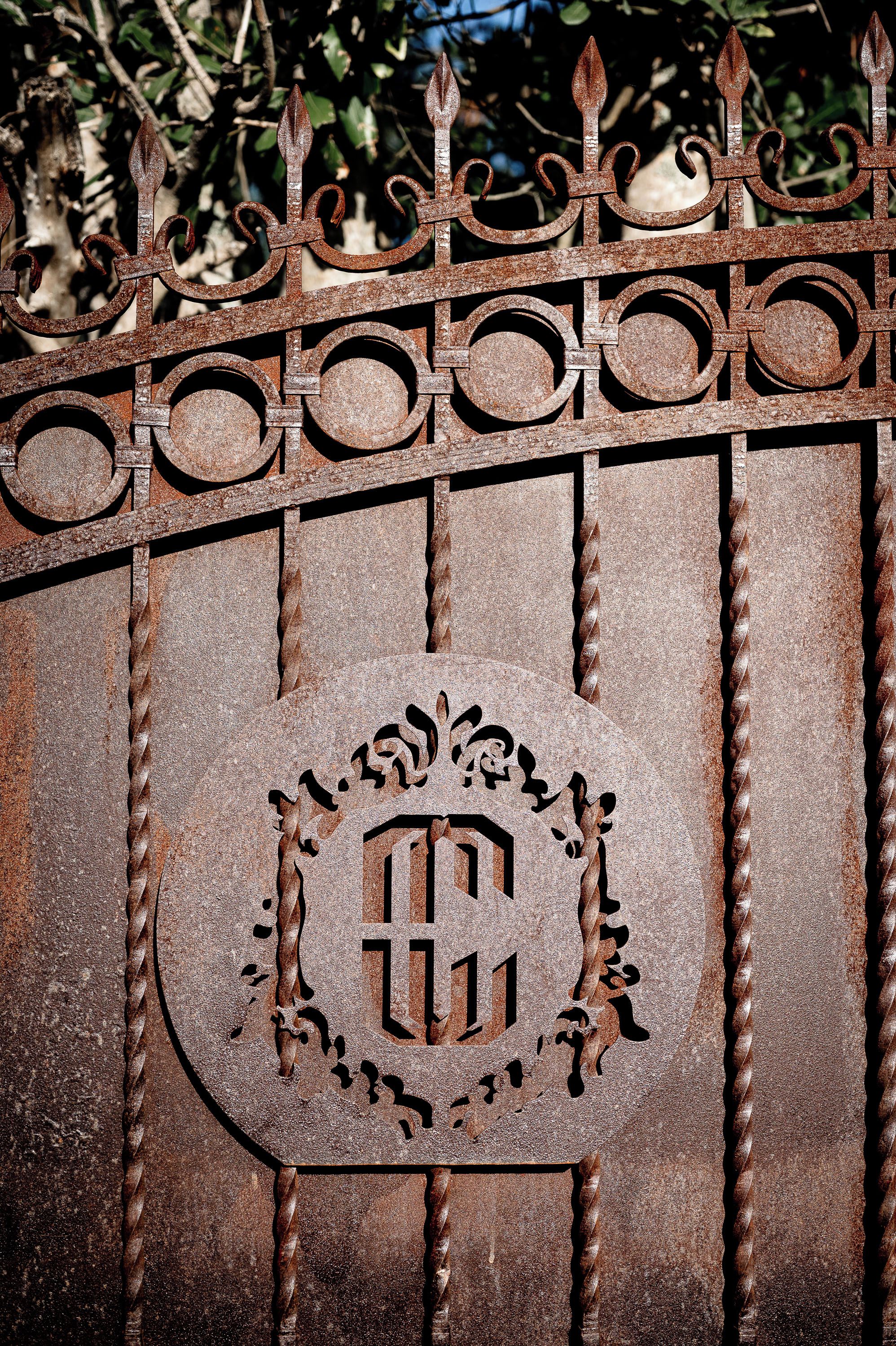 A wrought iron gate with a decorative crest and a central emblem.