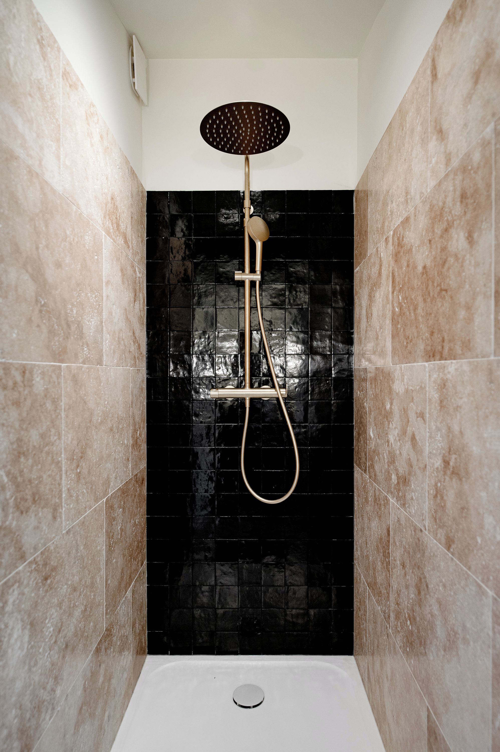 A shower with a handheld showerhead and a handheld shower attachment.