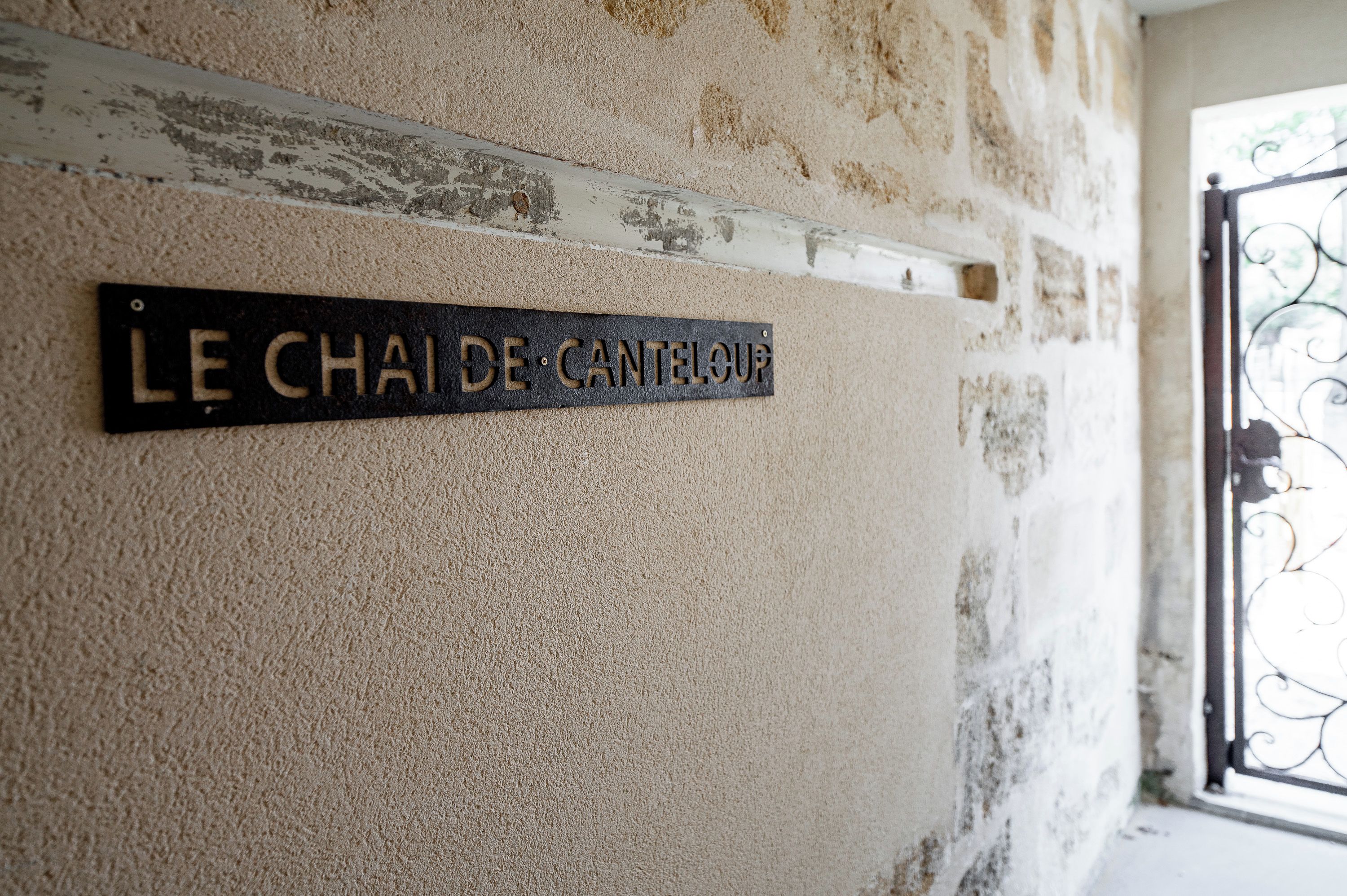 Ein Schild an einer strukturierten Wand, im Hintergrund ein Metallgitter.