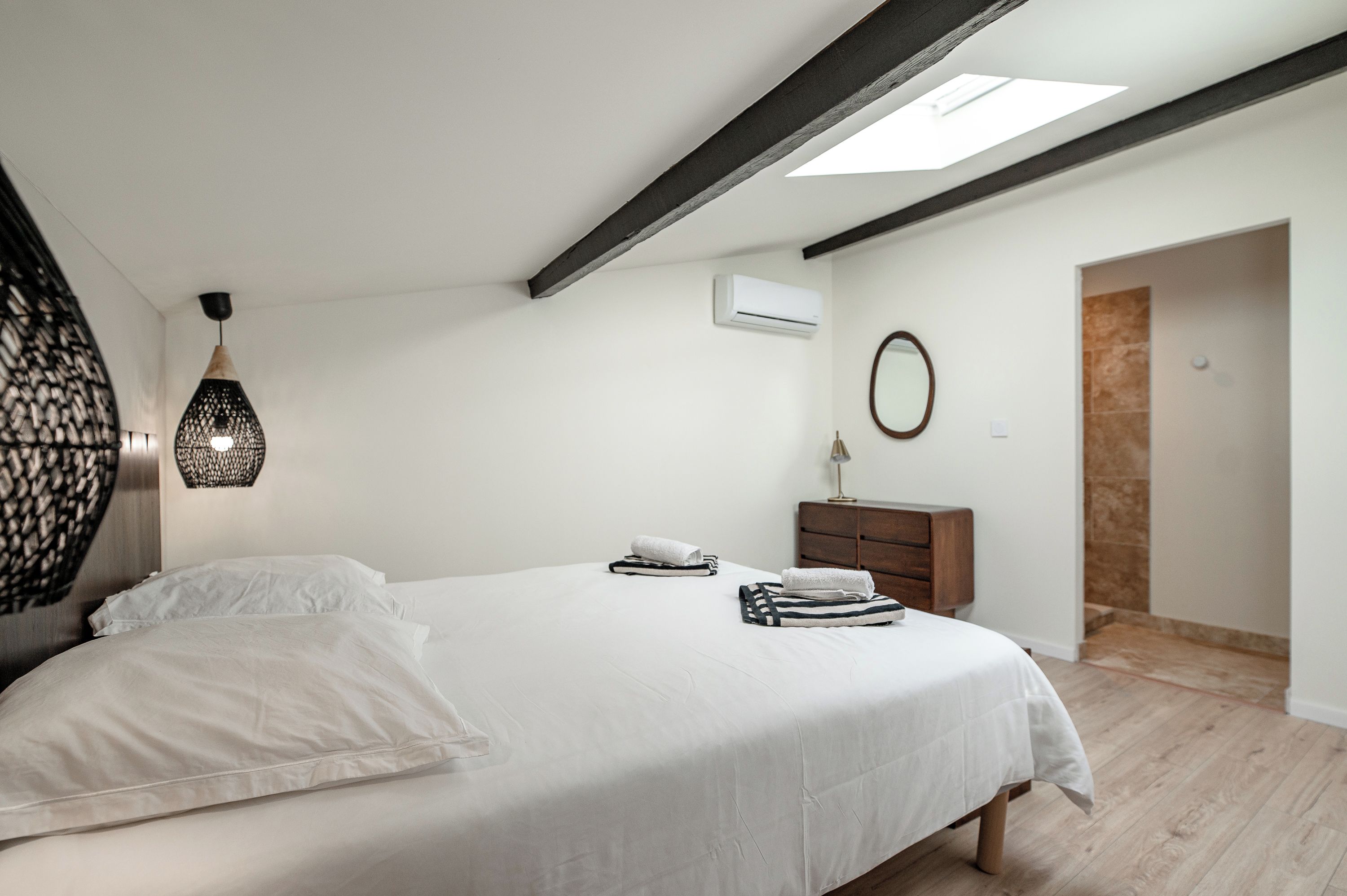 A bedroom with a bed, a dresser, a mirror, and an air conditioning unit.