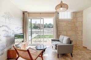 Una sala moderna con un sofá, un sillón, una mesa de centro y un televisor sobre un mueble de madera.