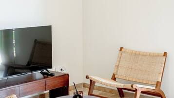 Una sala de estar moderna con televisor, muebles de mimbre y dos lámparas colgantes.
