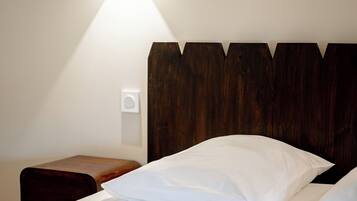 A hotel room with a bed, a bedside table, and a wall-mounted light fixture.