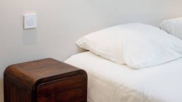 Een slaapkamer met een bed, een nachtkastje en een wandlamp.
