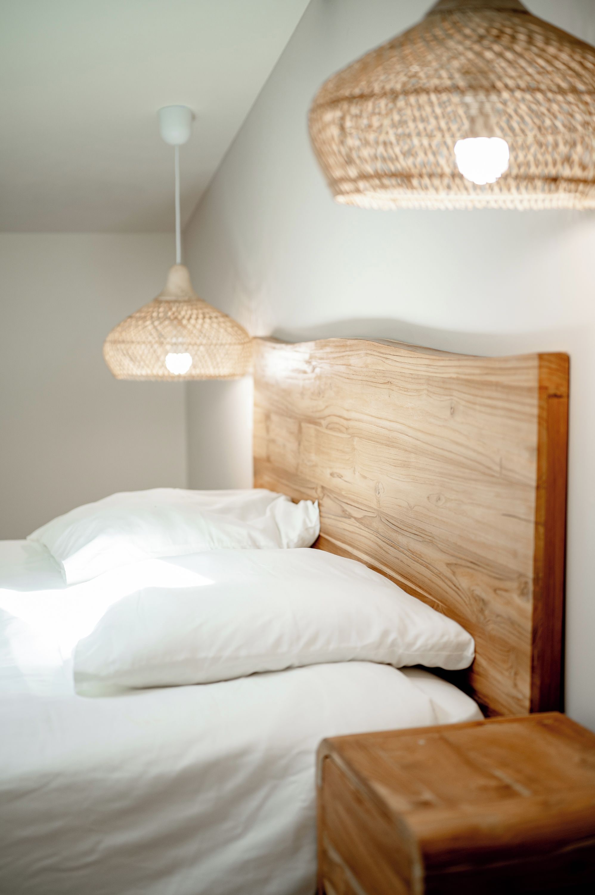 A bed with white bedding and a wooden headboard.