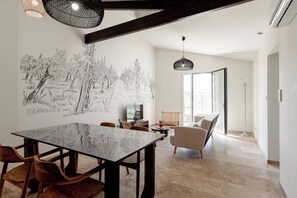 A modern interior with a dining area, a large wall mural, and a view to a balcony. - Le Chai de Canteloup (Yvrac)