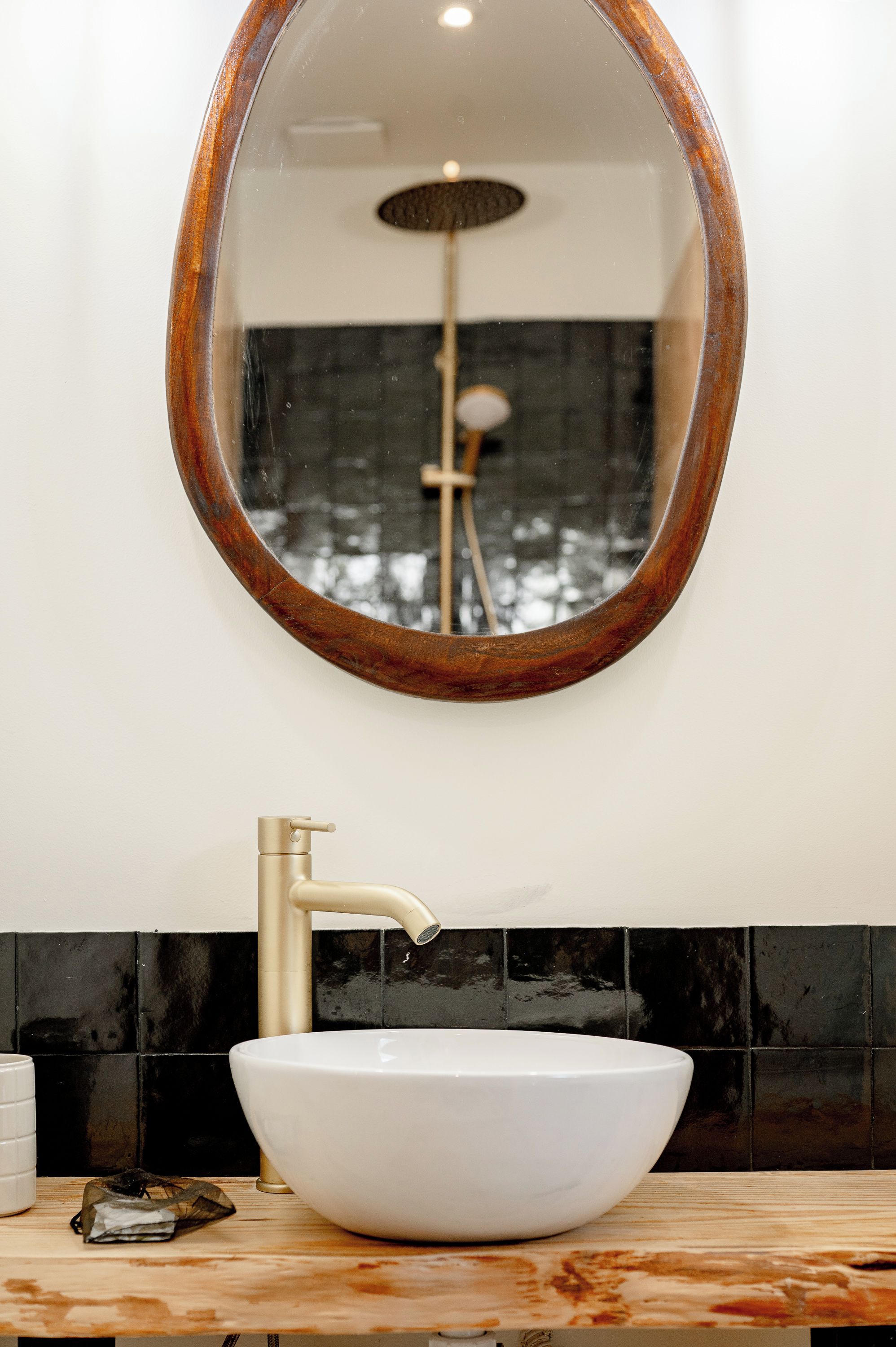 Un bagno con un lavandino bianco, un rubinetto dorato e uno specchio con cornice in legno.