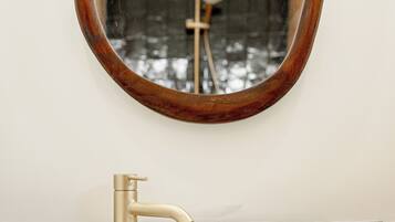 Un bagno con un lavandino bianco, un rubinetto dorato e uno specchio con cornice in legno.