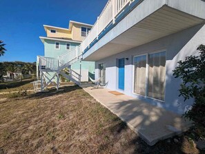 A two-story building with a covered outdoor area and a staircase leading to the upper level. - Beach Retreat - One Block to the Water! (Flalger Beach)