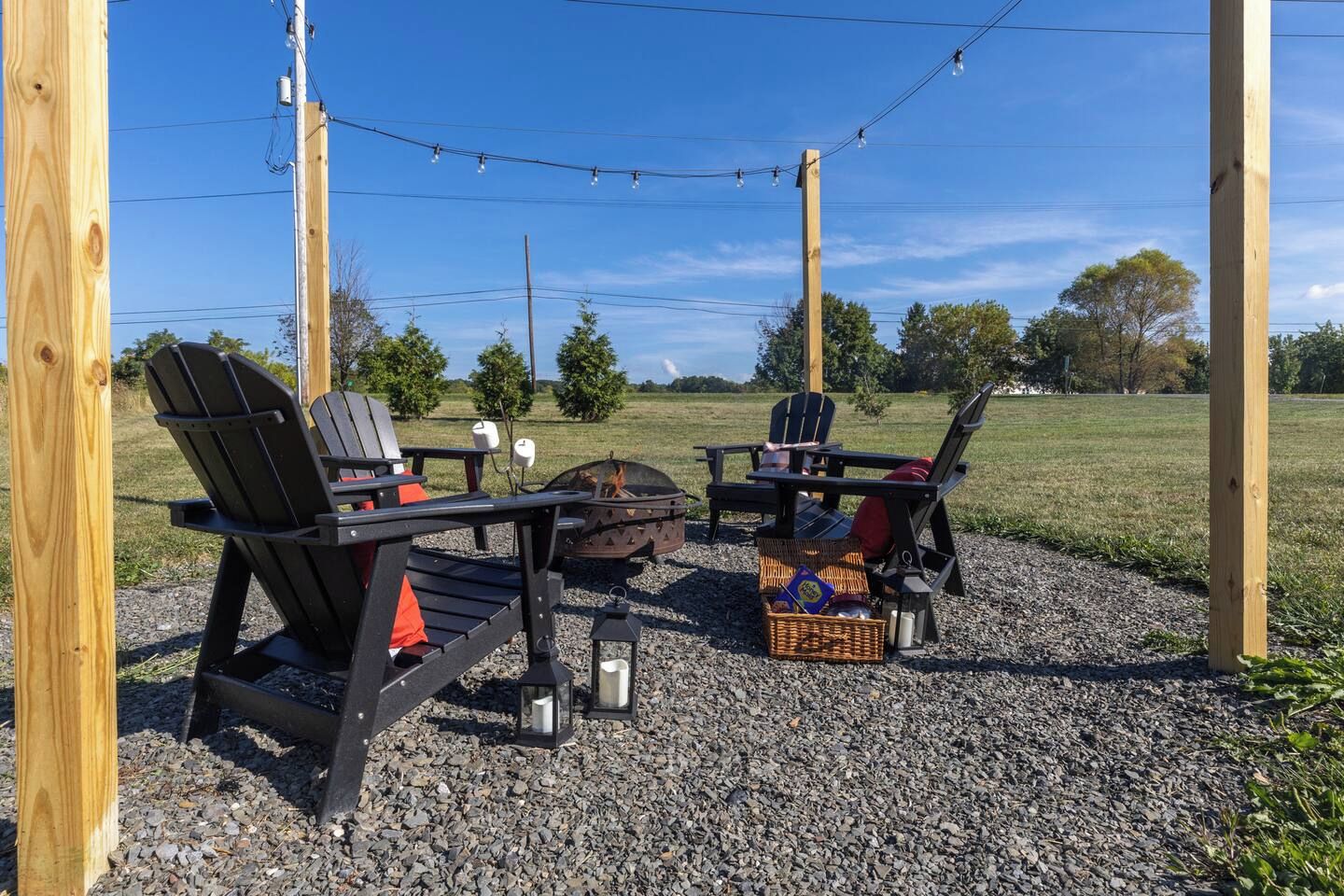 An outdoor seating area with Adirondack chairs, a fire pit, and a table.
