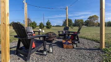 An outdoor seating area with Adirondack chairs, a fire pit, and a table.