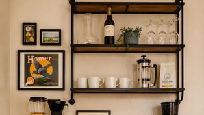 Una kitchenette con cafetera, una botella de vino y libros en un mueble verde.