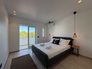 A modern bedroom with a large bed, a sliding glass door to a balcony, and pendant lighting. - Agua Plaza T2 With Pool AC (Albufeira)
