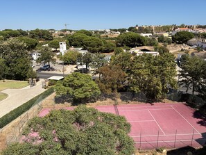 A residential area with a tennis court, trees, and buildings in the background. - Agua Plaza T2 With Pool AC (Albufeira)