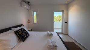 Hotellihuone, jossa on sänky, ikkuna, ovi ja kattovalaisin.