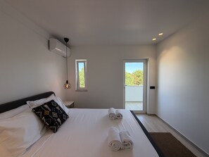 A hotel room with a bed, a window, a door, and a ceiling light fixture. - Agua Plaza T2 With Pool AC (Albufeira)