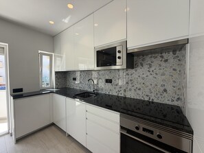 A modern kitchen with white cabinets, a granite countertop, a built-in microwave, and a stainless steel range hood. - Agua Plaza T2 With Pool AC (Albufeira)