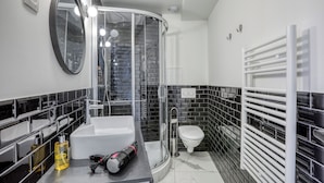 Un baño moderno con ducha de vidrio, lavamanos blanco y un inodoro.