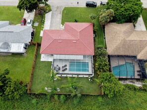A residential property with a swimming pool, a covered patio, and a red roof. - Tropicana Bungalow with Heated Pool, Pool Table & Tropical Vibes (Fort Myers)