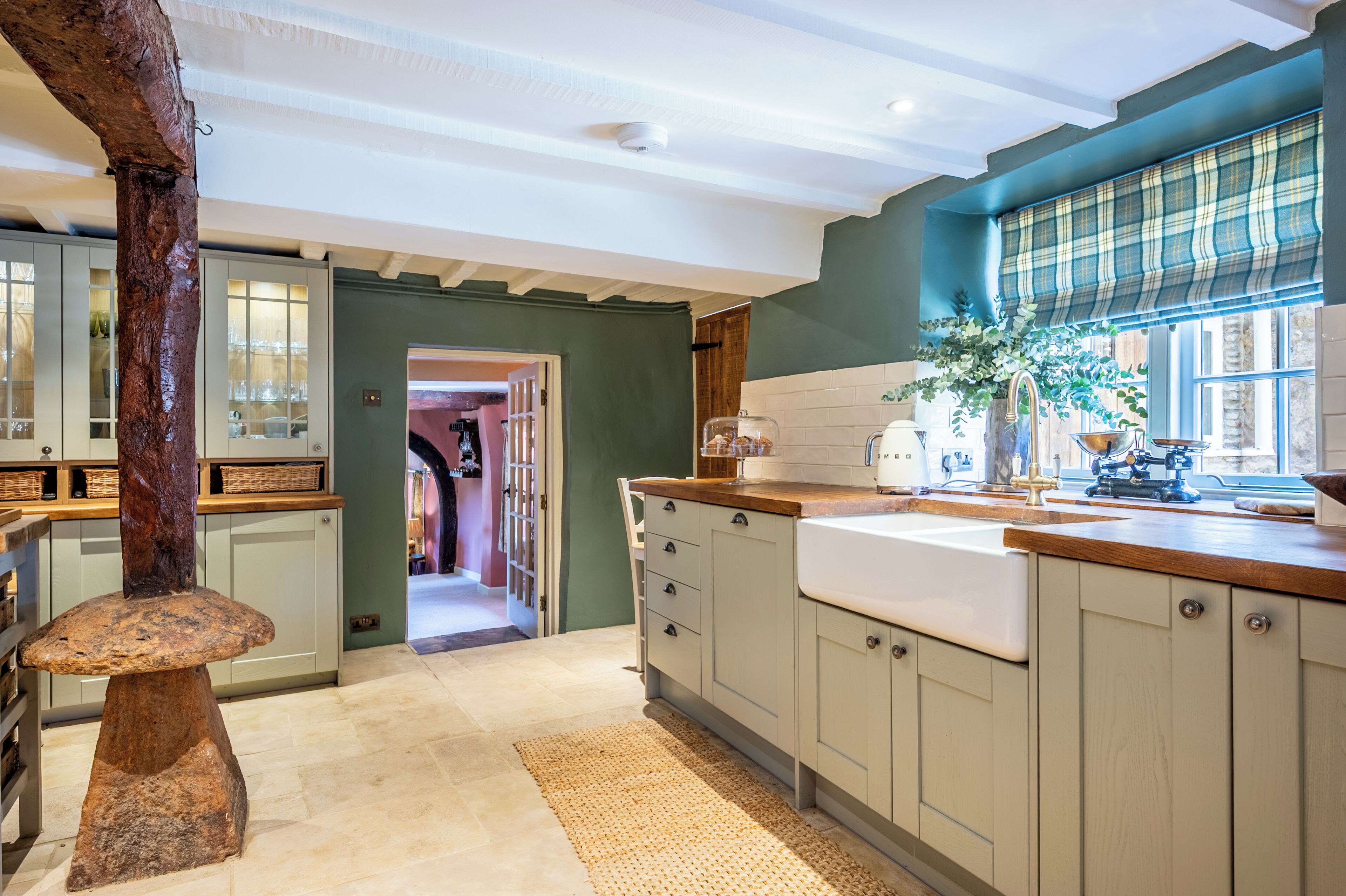 A kitchen with a large island, wooden cabinets, a window with a view, and a door leading to another room.