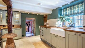 A kitchen with a large island, wooden cabinets, a window with a view, and a door leading to another room.
