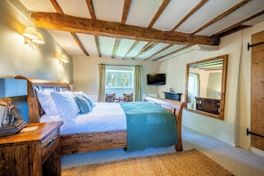 A bedroom with a wooden bed, a television, and a large mirror.