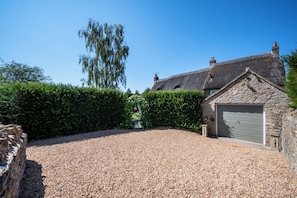 A stone building with a gravel driveway and a garage.