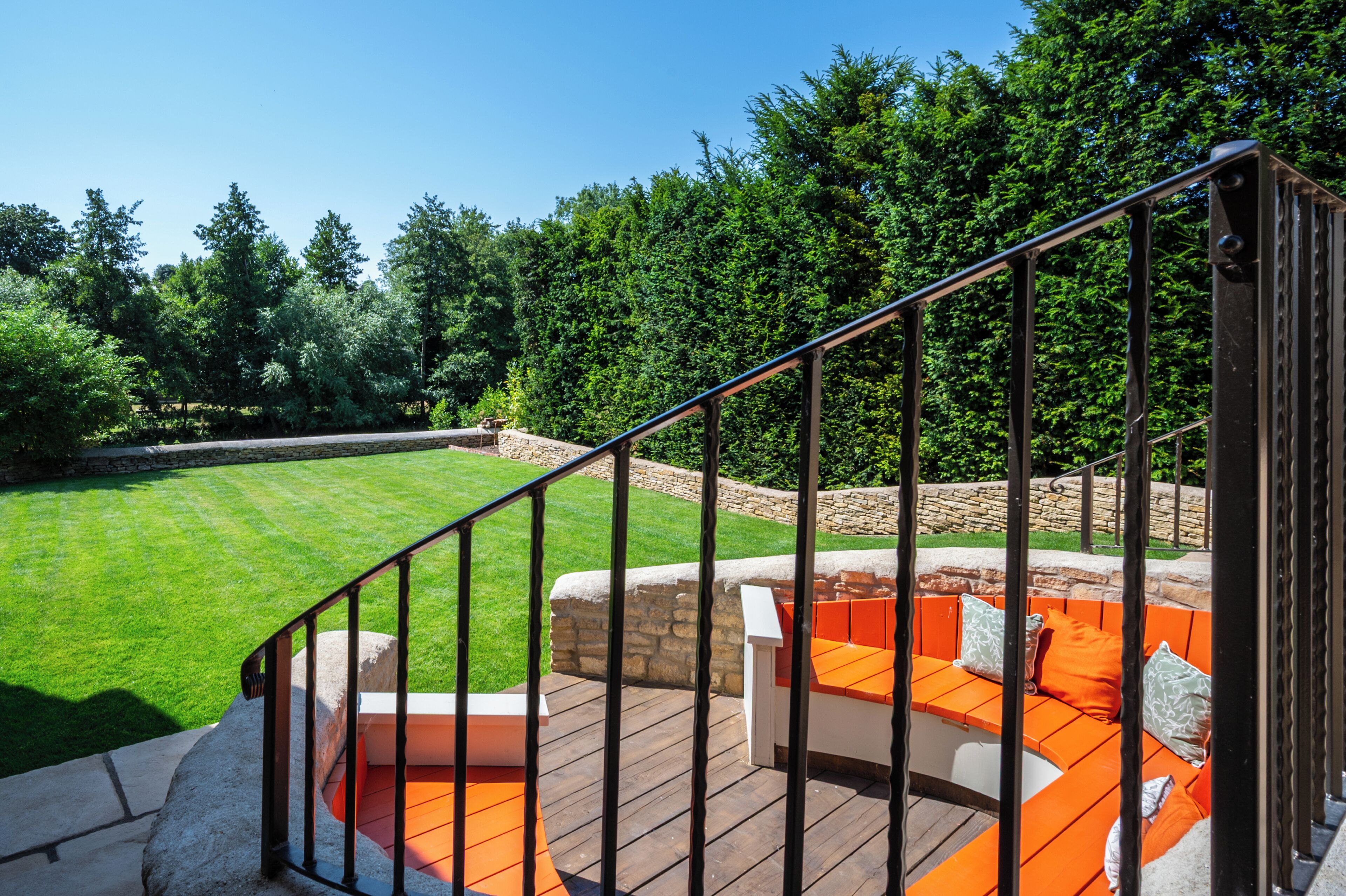 A wooden deck with orange seating and a stone wall.