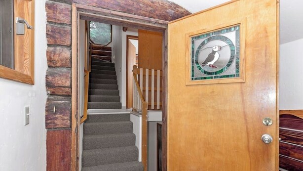 A wooden door with a glass panel and a bird design, leading to a staircase with a wooden railing. - A Hexagonal Cabin in the Trees, Two Miles From Alyeska (Girdwood)