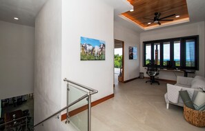Ein großzügiger Wohnbereich mit großem Fenster, Deckenventilator und Wand-Fernseher.