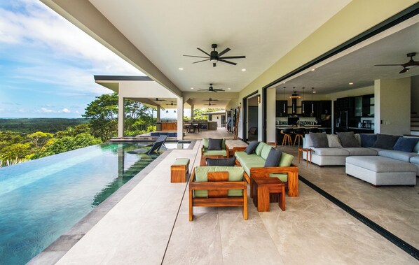 Uma área externa moderna com piscina, espaço para sentar e vista para a paisagem.
