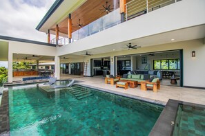 A modern house with a large indoor swimming pool, outdoor seating, and a kitchen area. - Villa Serenity, 4-bedroom luxury ocean view with Pool and Trails Near Dominical (Uvita)