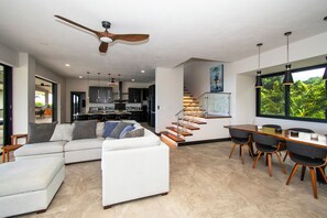 Um espaço de estar moderno com sofá, mesa de jantar e escada.