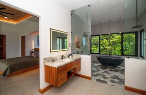 Une salle de bain moderne dotée d’une grande baignoire, d’une douche à parois de verre et d’un meuble-lavabo avec un plan de travail en marbre.